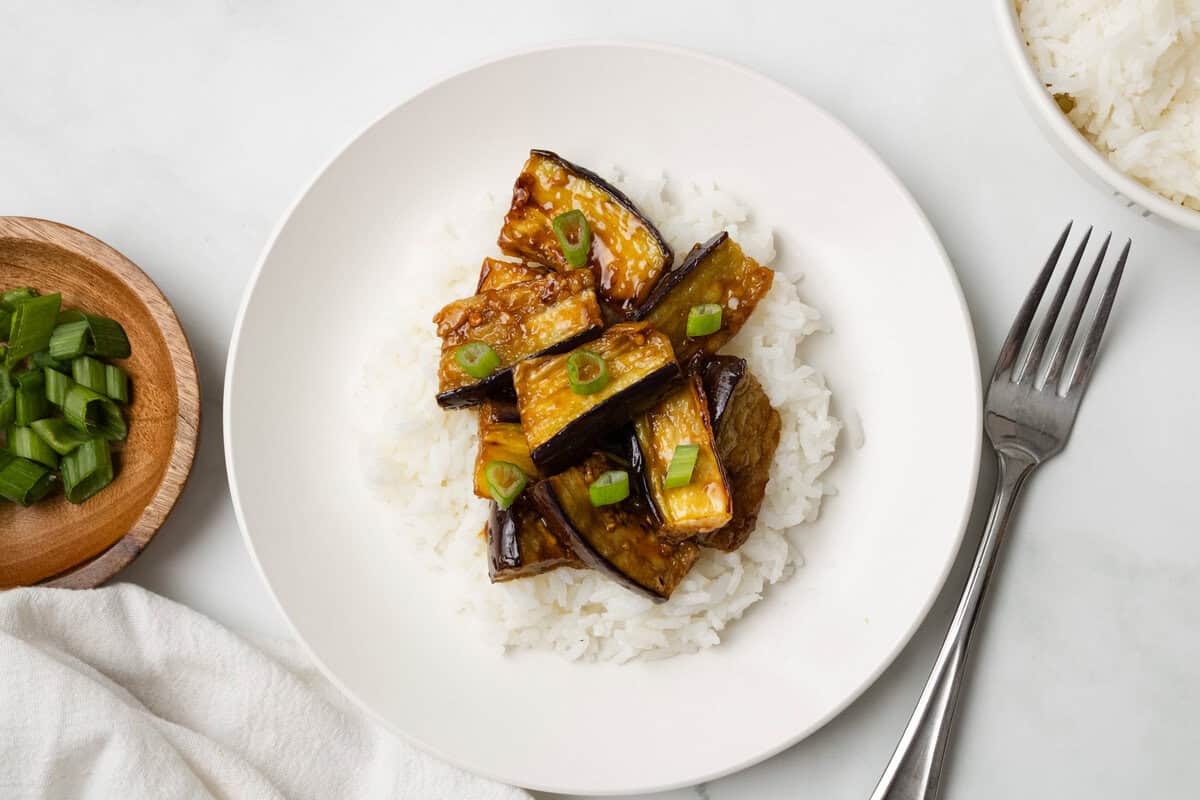 An overhead image of eggplant stir fry served over rice on a plate.