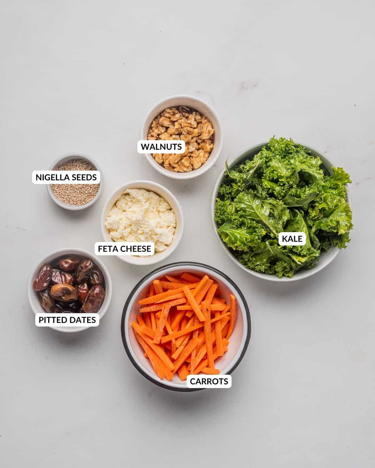 An image of kale salad ingredients in separate bowls with labels.