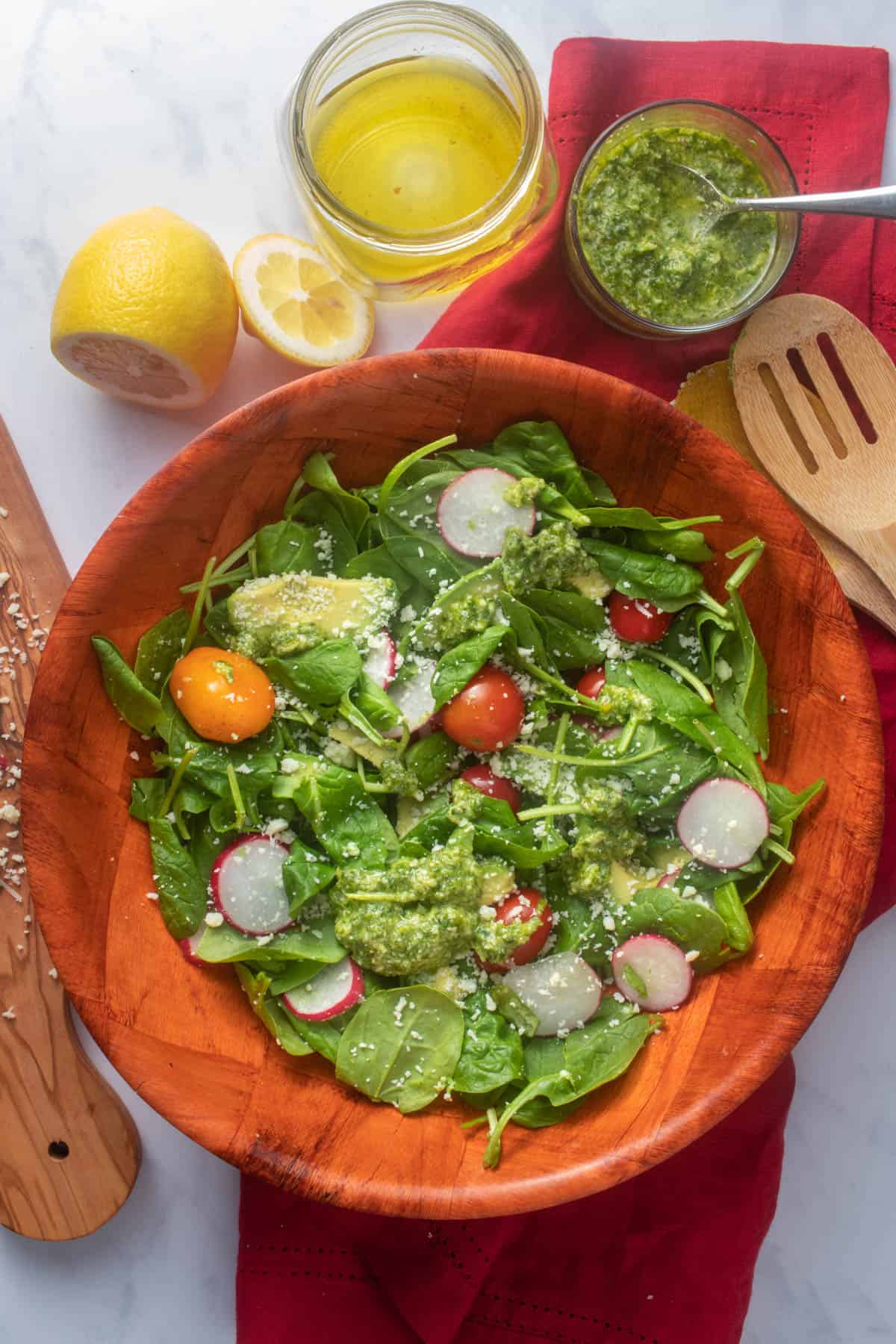 Bowl of spinach avocado salad with green goddess dressing, lemony vinaigrette in background