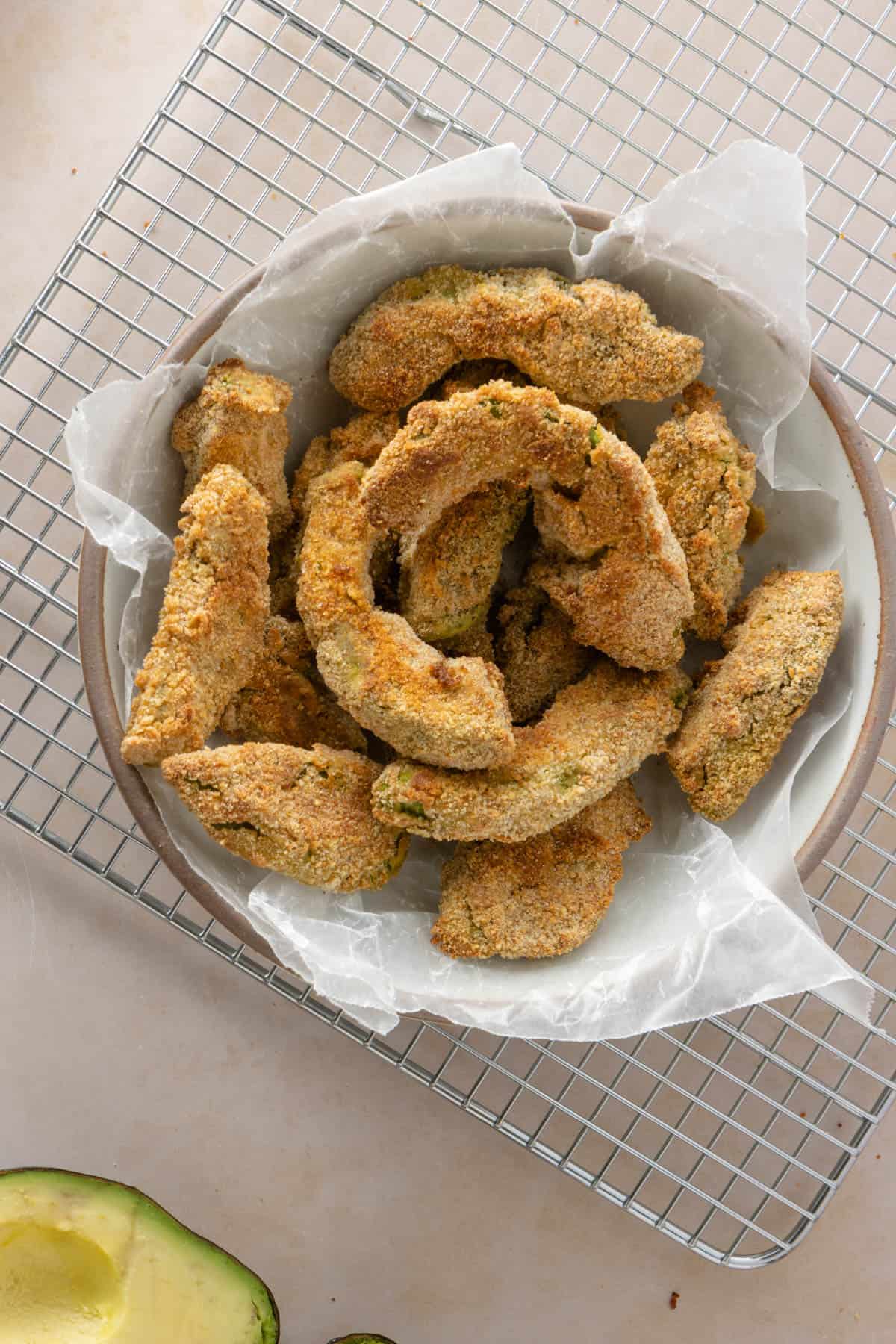 Bowl of avocado fries laying on a cooling rack