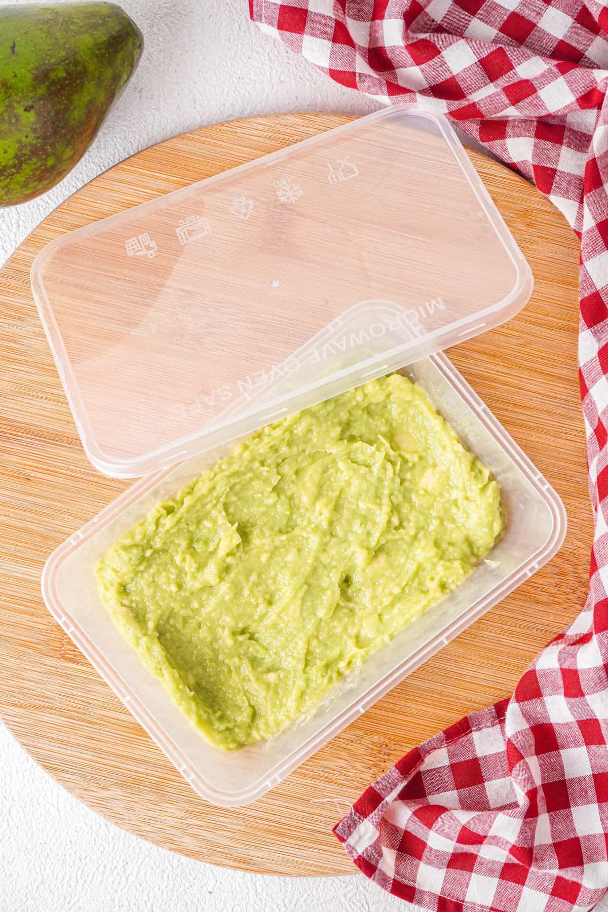 Overhead view of mashed avocados in freezer-safe container