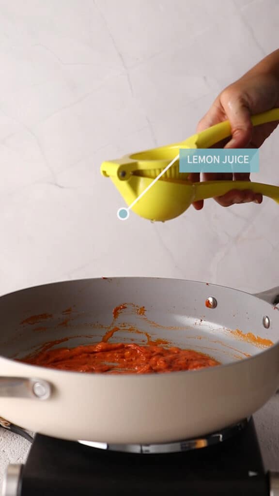Sideview of squeezing lemon juice into sauce with a squeezer.