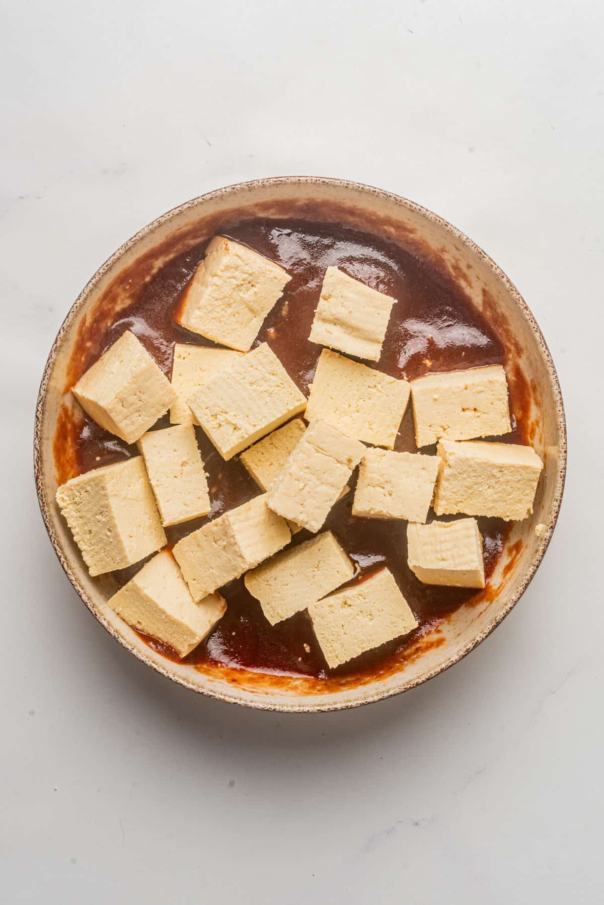 An image of a tofu added in a bowl of the gochujang sauce mixture.