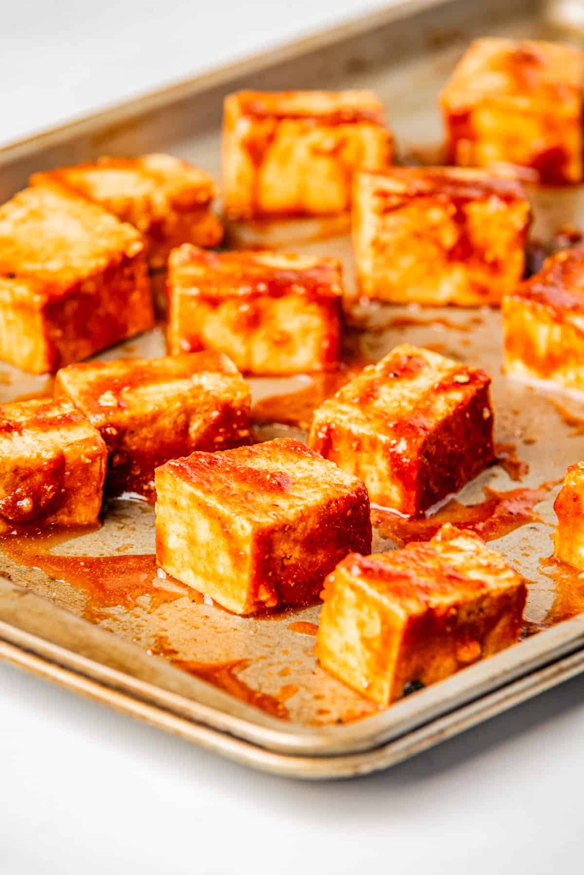 A close up image of gochujang sauce-coated tofu in a baking pan.