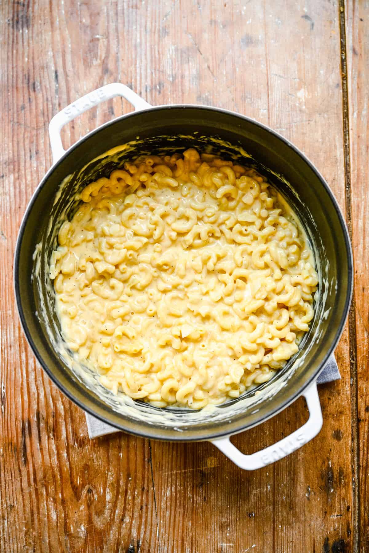 Overhead view of cooked cheese sauce in a large sauce pan added with drained macaroni.