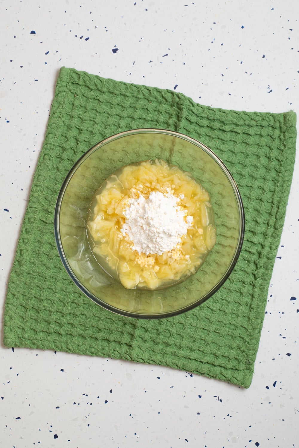 Crushed pineapple and pudding added in a glass bowl.