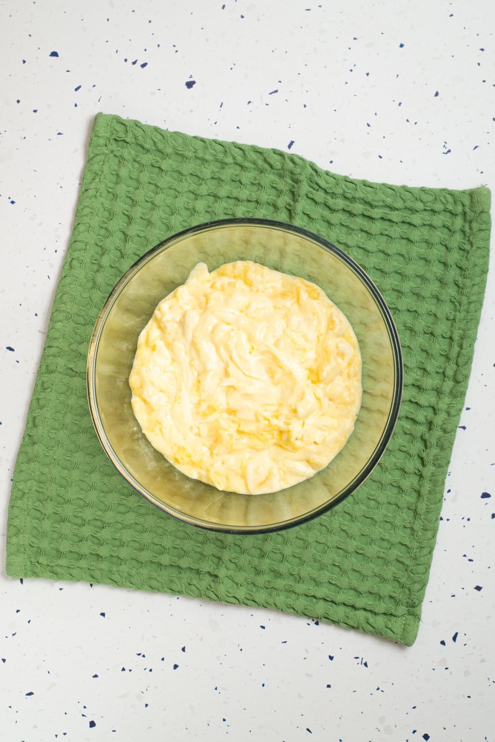 Pineapple and pudding mixture combined with whipped topping in a glass bowl.