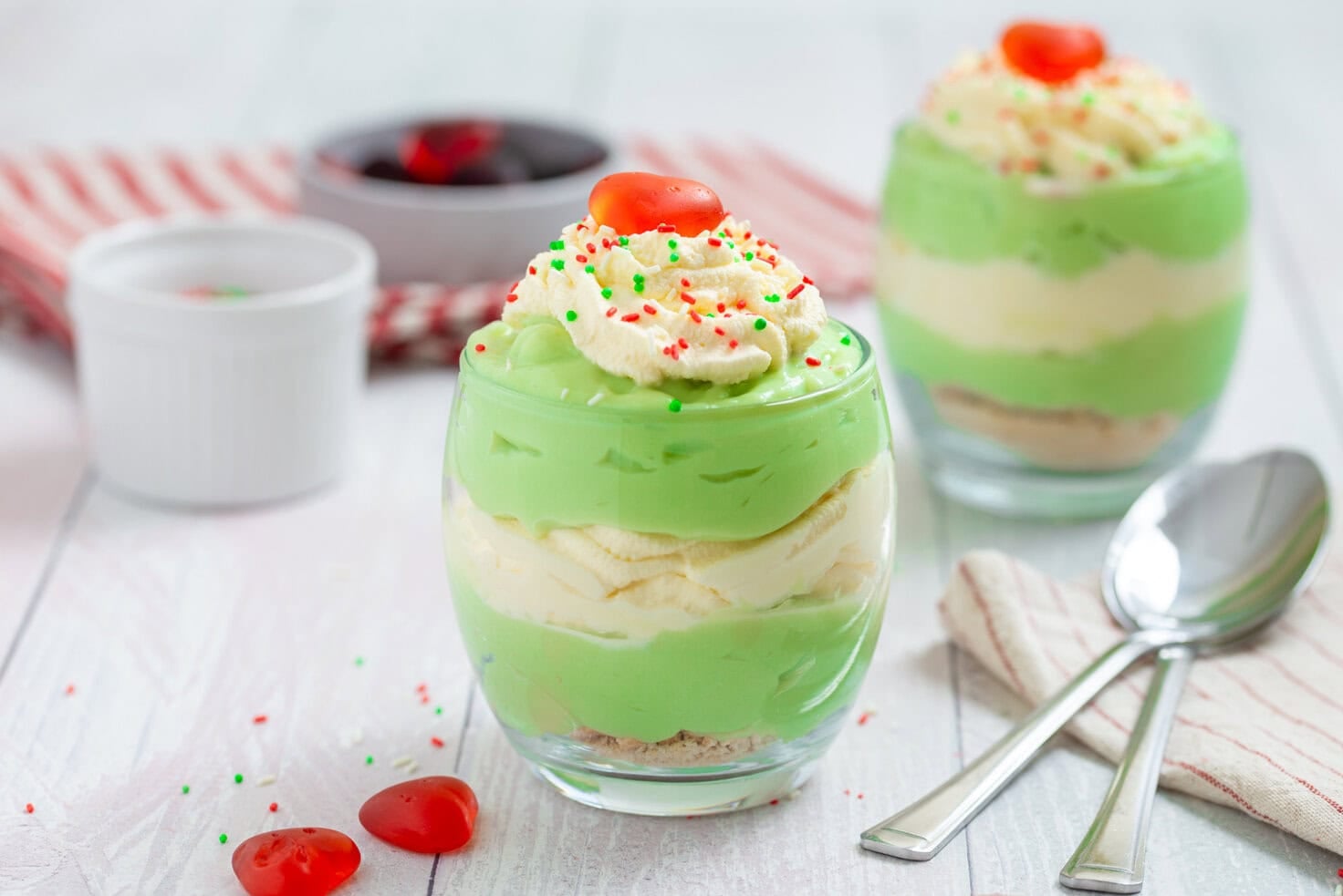 Grinch Who Pudding parfaits layered with green pudding and whipped cream, topped with sprinkles and red candy hearts.