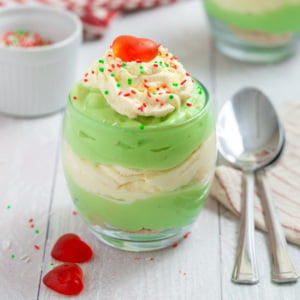 Grinch Who Pudding layered with green pudding, whipped cream, Christmas sprinkles, and a red candy heart.