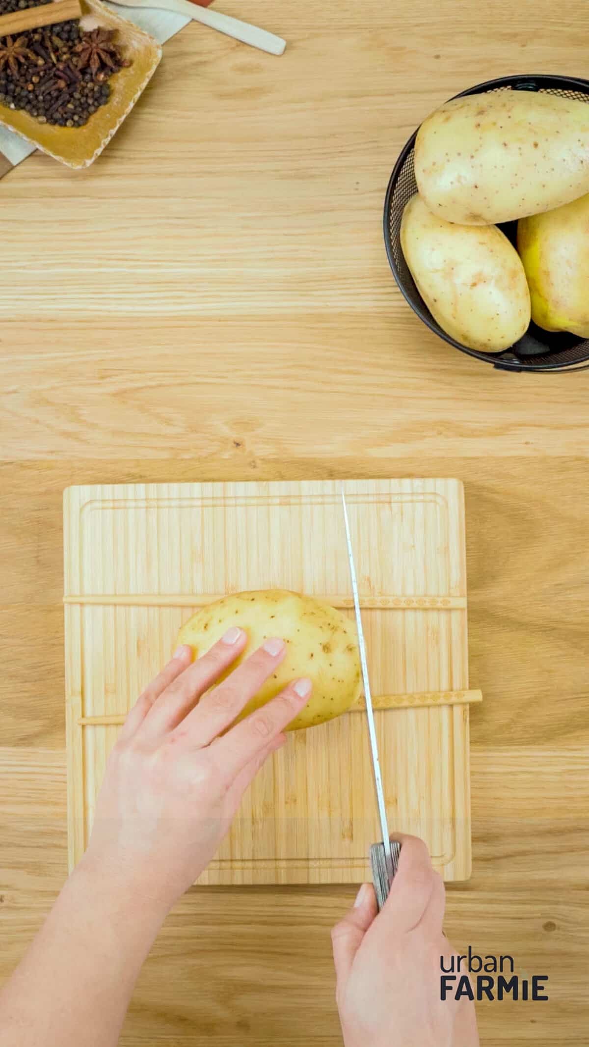 An image of a potato being slit on a chopping board.