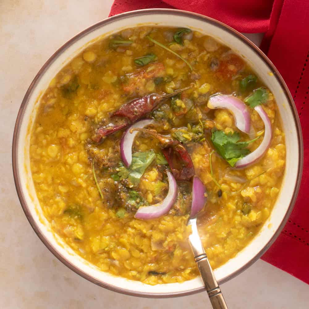Close up of bowl with dal tadka showing all the garnishes