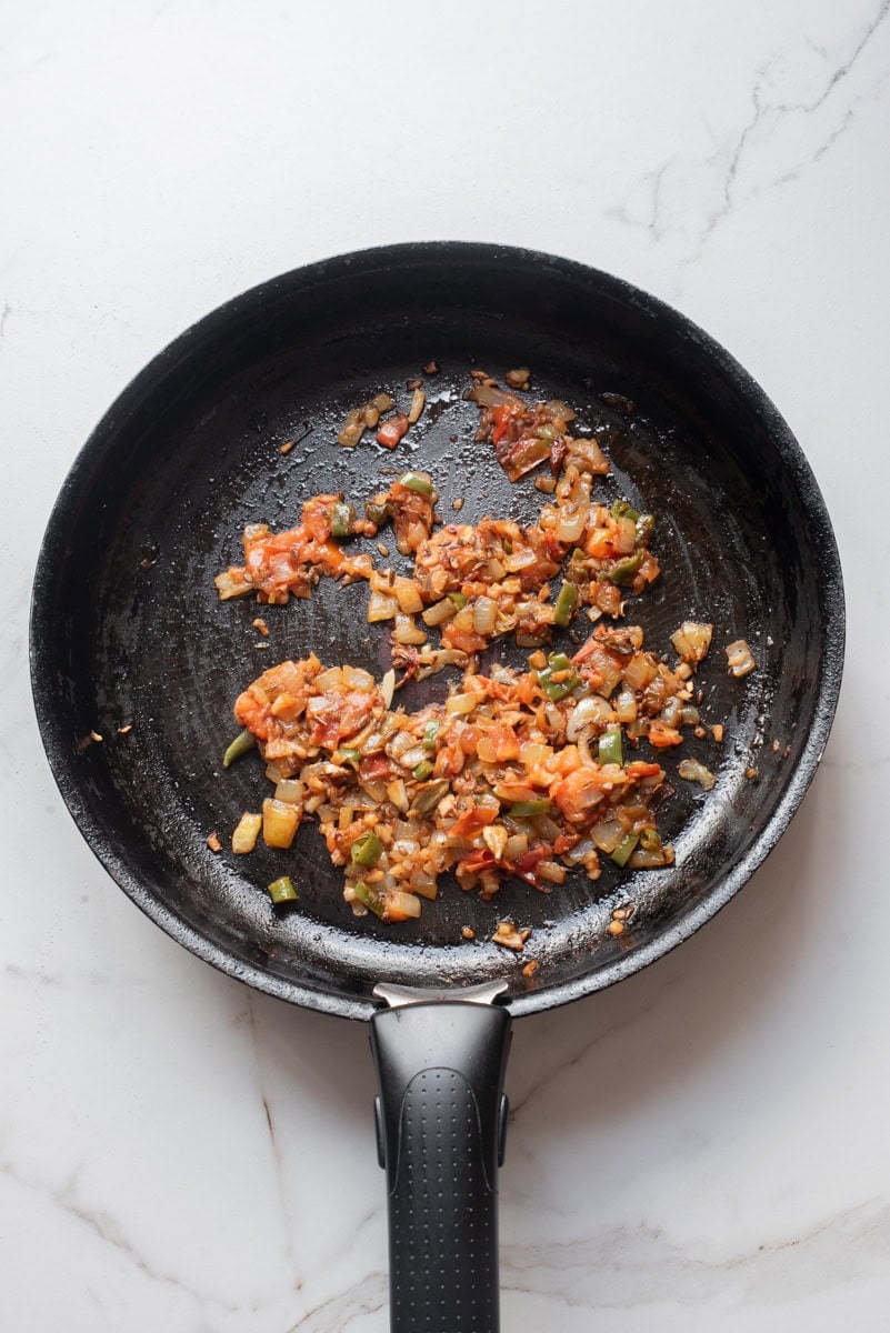An overhead image of adding the tomatoes to the skillet.