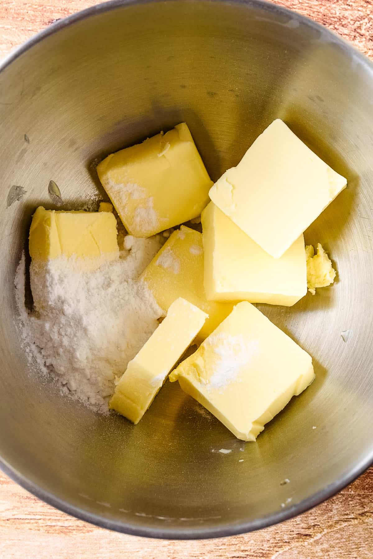Overhead view of butter and sugar in a mixing bowl.