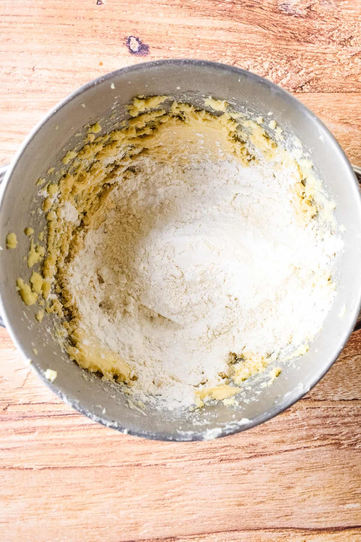 Overhead view of dry ingredients added to wet ingredients in mixing bowl.