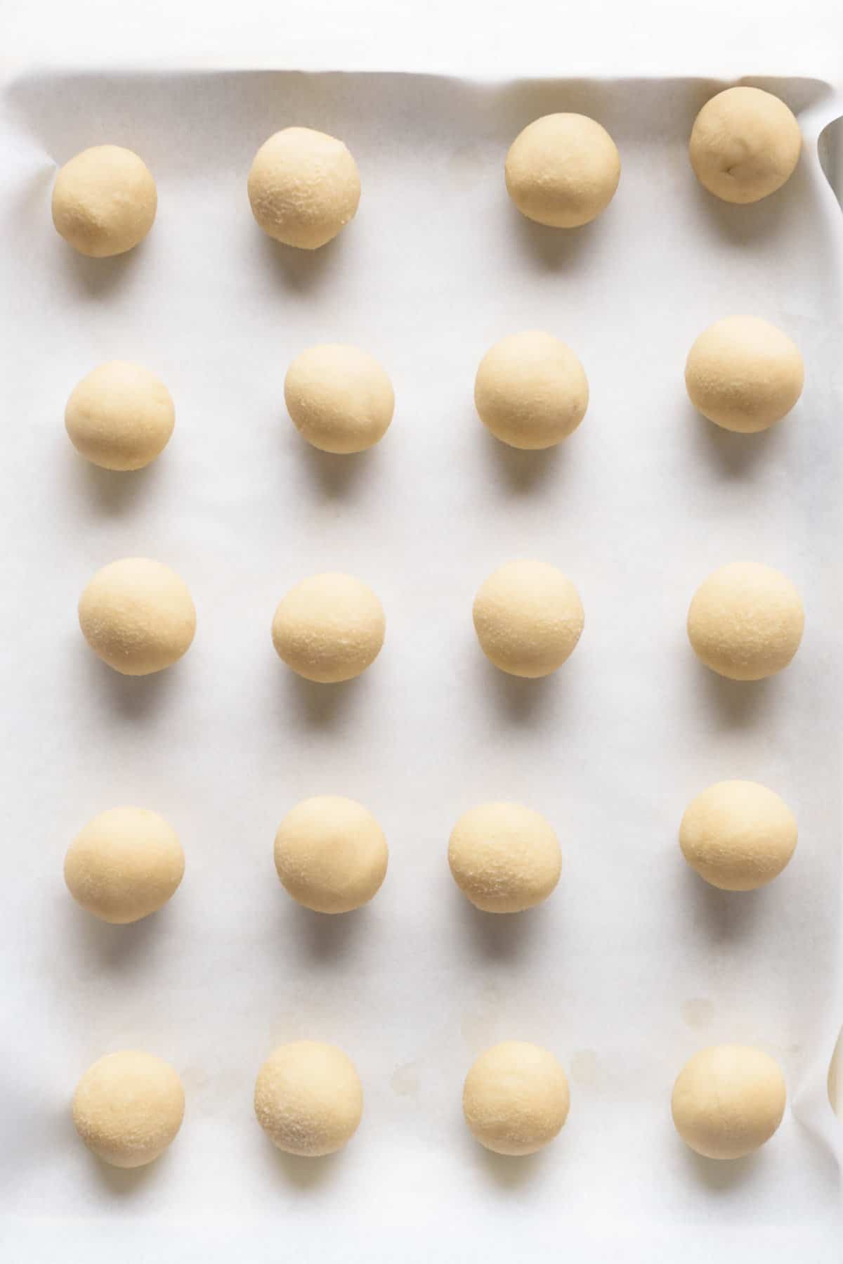 Overhead view of cookie dough balls on baking sheet.