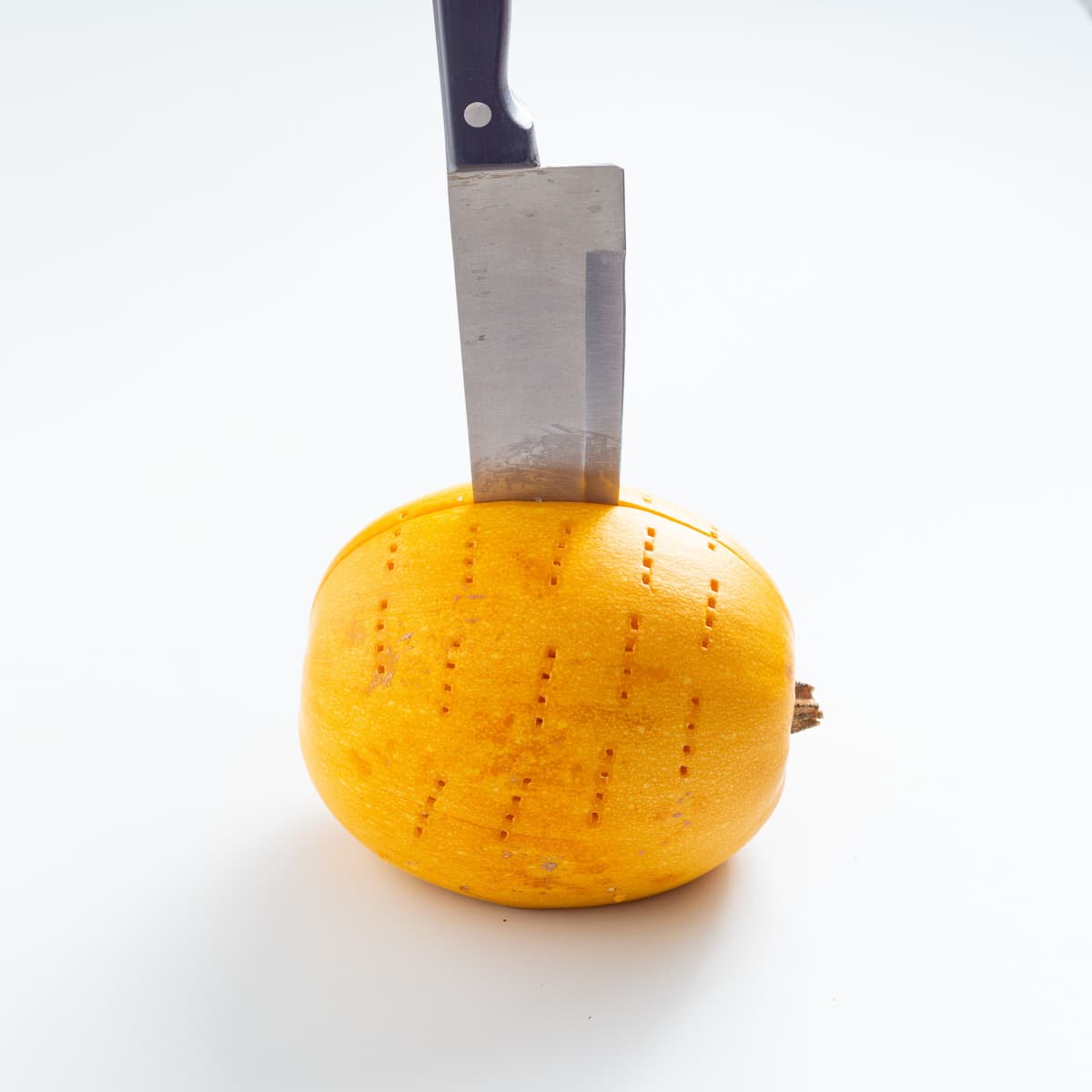 A straight view of a knife cutting the spaghetti squash in half.