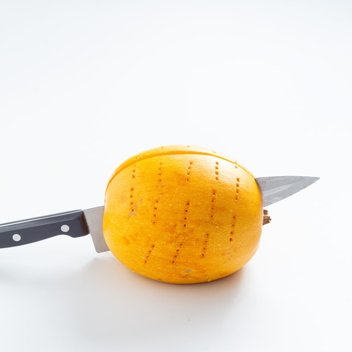 A straight photo of a knife successfully cutting the spaghetti squash in half. 