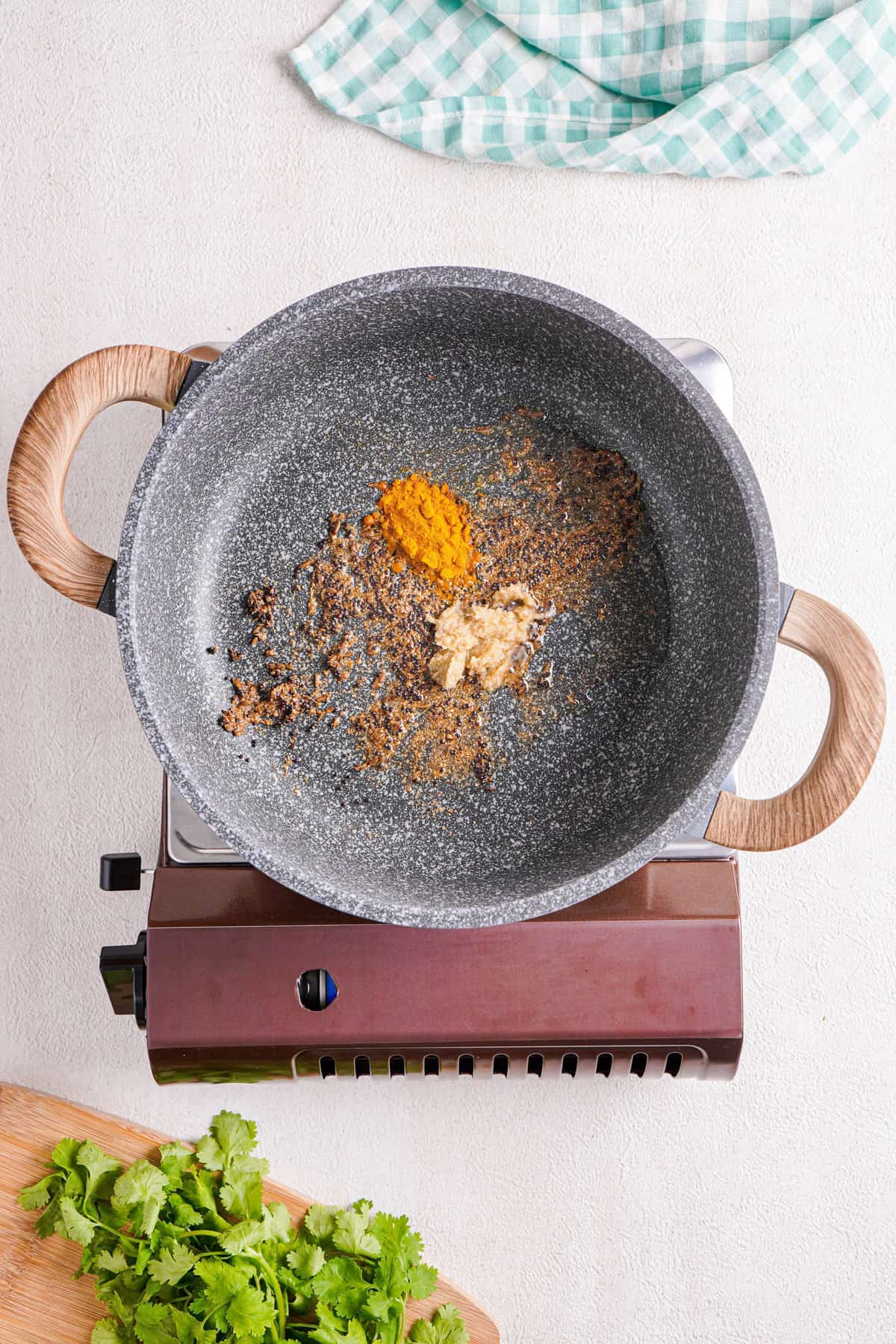 Overhead view of spices being toasted (including turmeric) in a skillet.