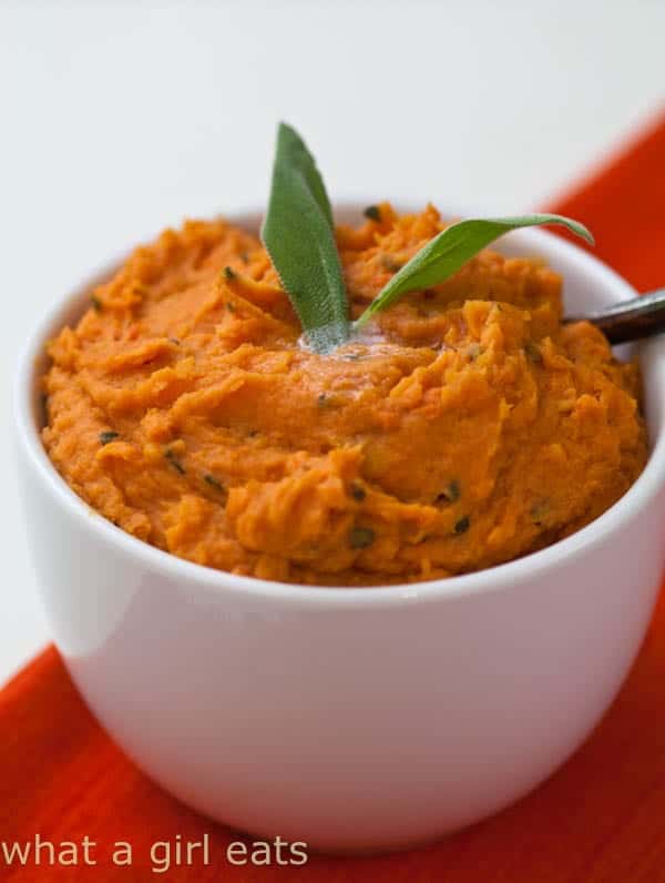 Straight view of mashed sweet potatoes with browned butter and sage placed on a small white bowl.