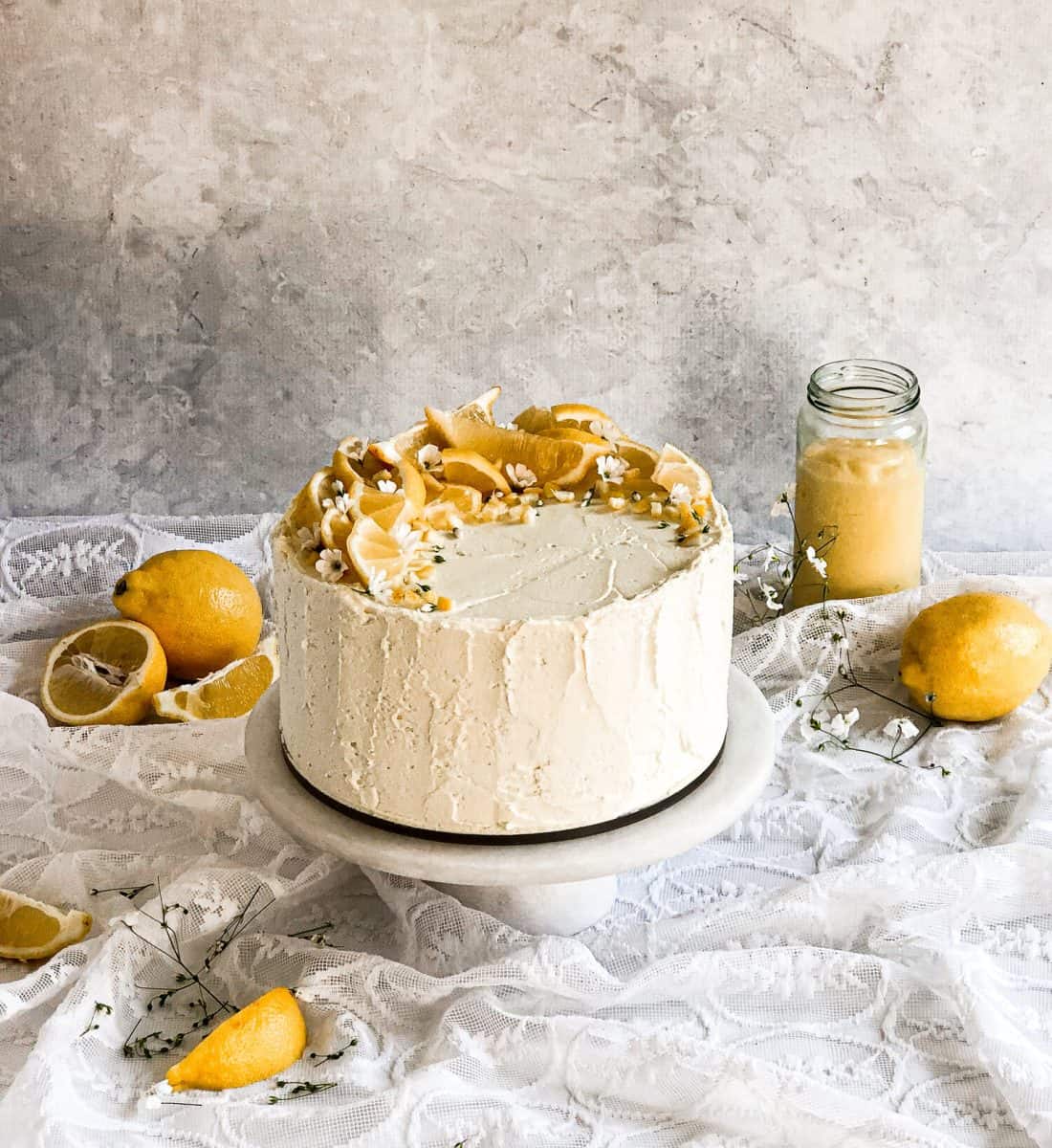 A straight view of dairy-free lemon cake with dried lemons in the background.