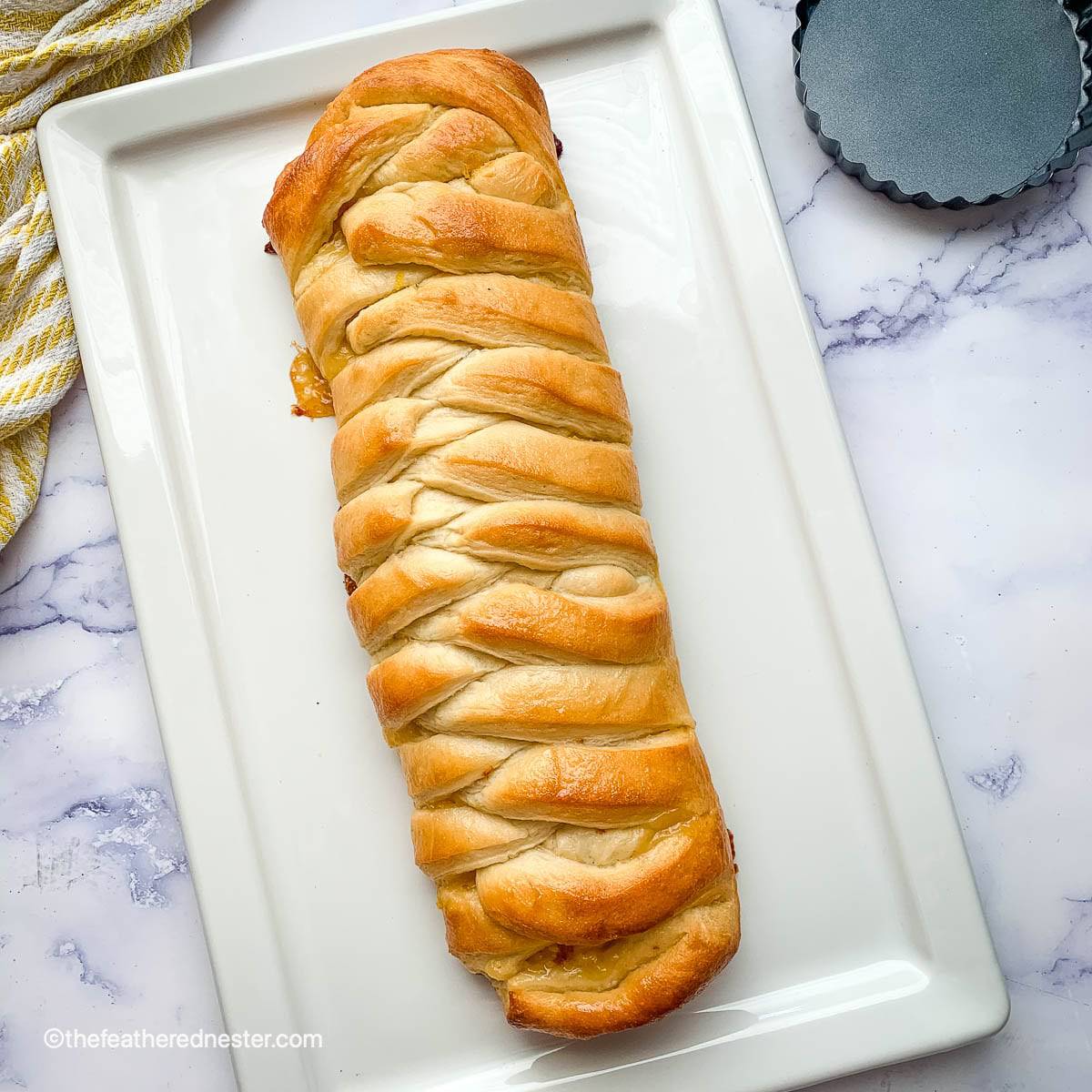 Overhead view of a lemon braided bread loaf placed on a white plate.