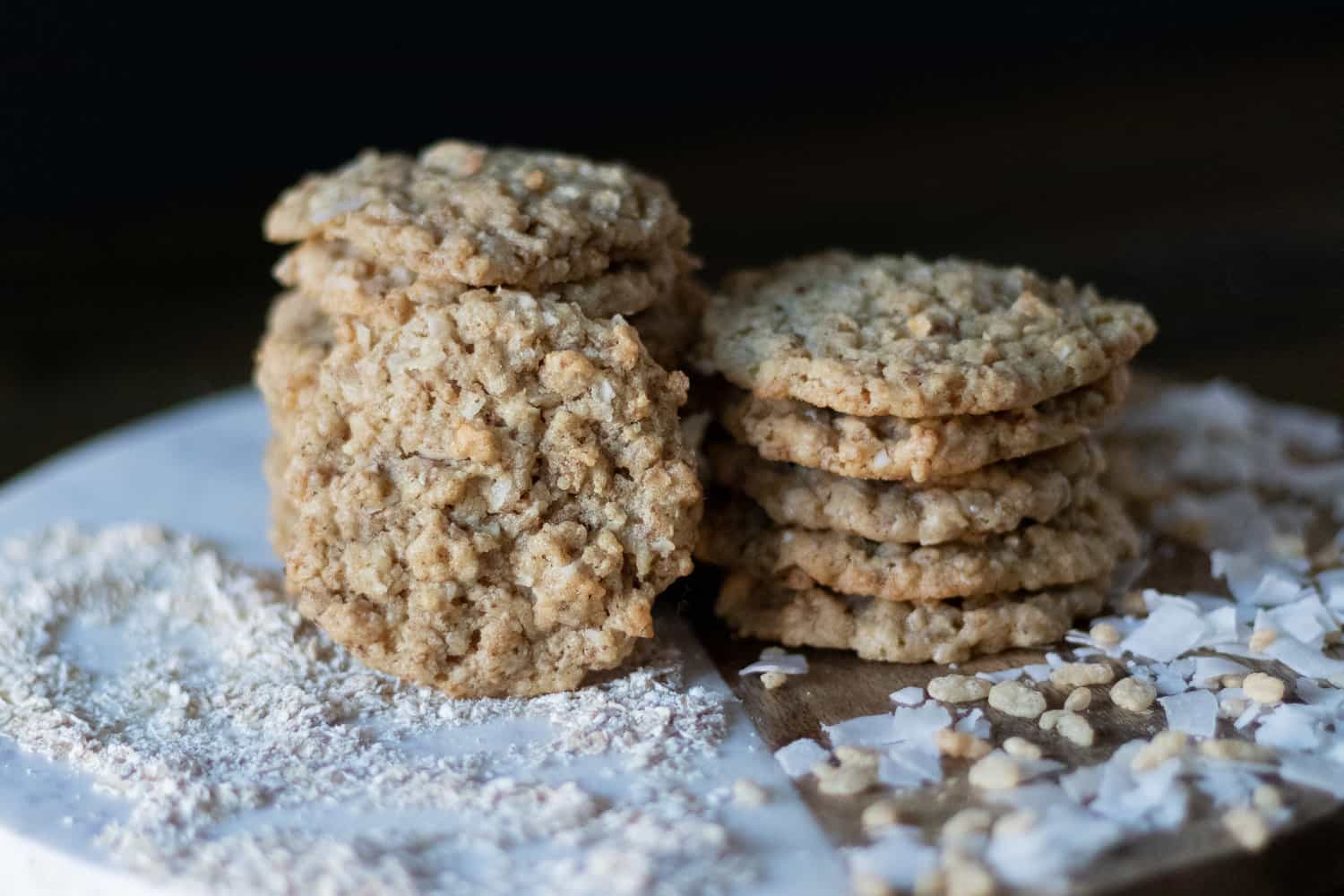 A straight view of stacked vegan ranger cookies with coconut, oats, and rice cereal spread on the sides.