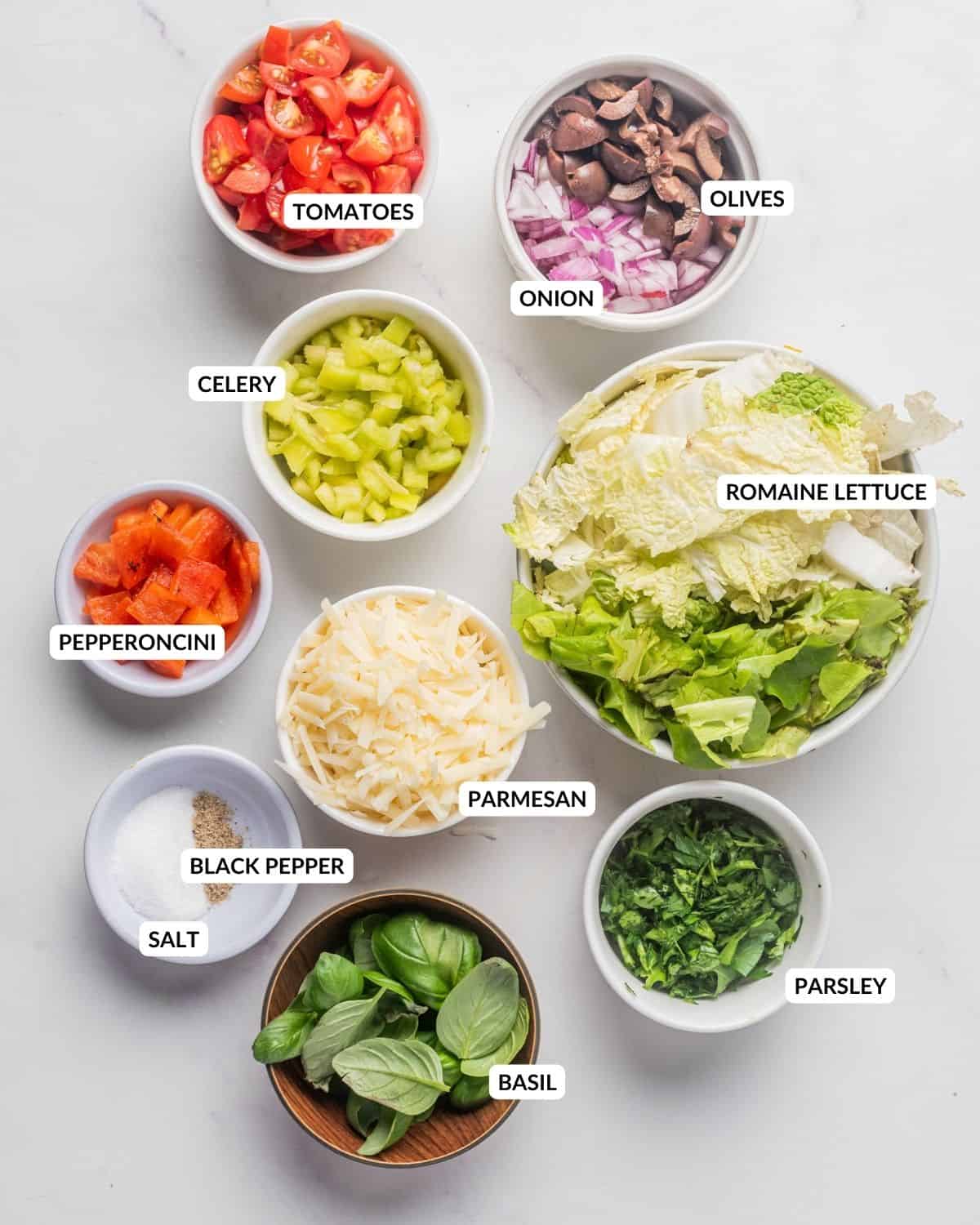 An image of all the labeled ingredients of Italian chopped salad, in separate bowls. 