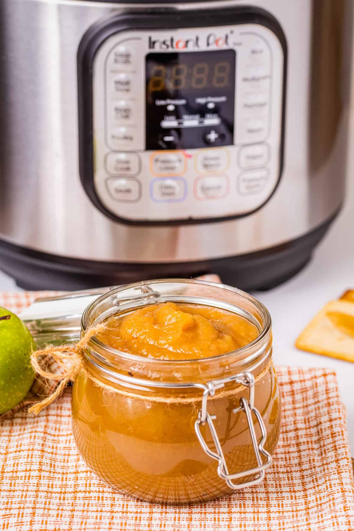 Close up of apple butter in a glass jar, with Instant Pot in the background.