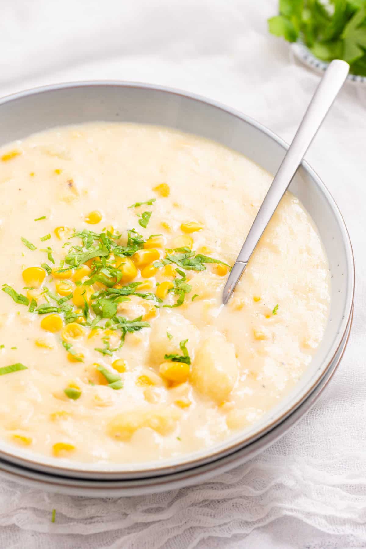 A close up image of instant pot corn chowder in a bowl with a spoon in it.