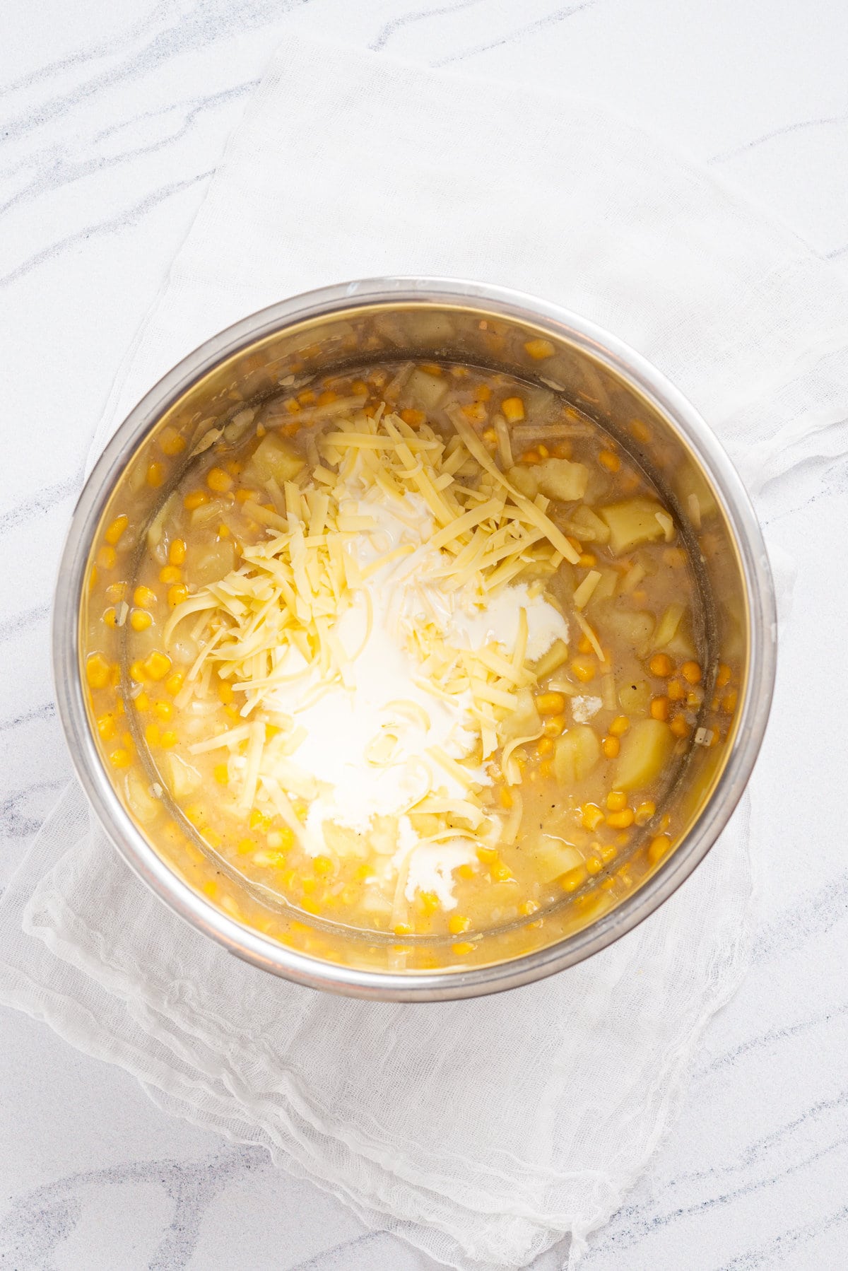 An overhead image of adding half and half and cheese to the instant pot.
