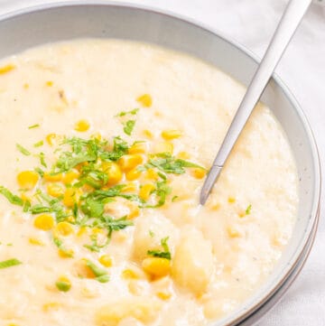 A close up image of instant pot corn chowder in a bowl with a spoon in it.