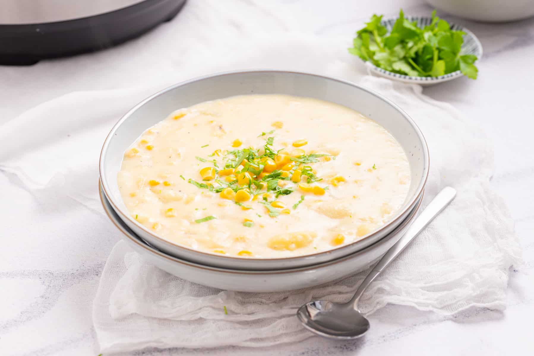 An image of instant pot corn chowder in a bowl with a spoon resting on the side.