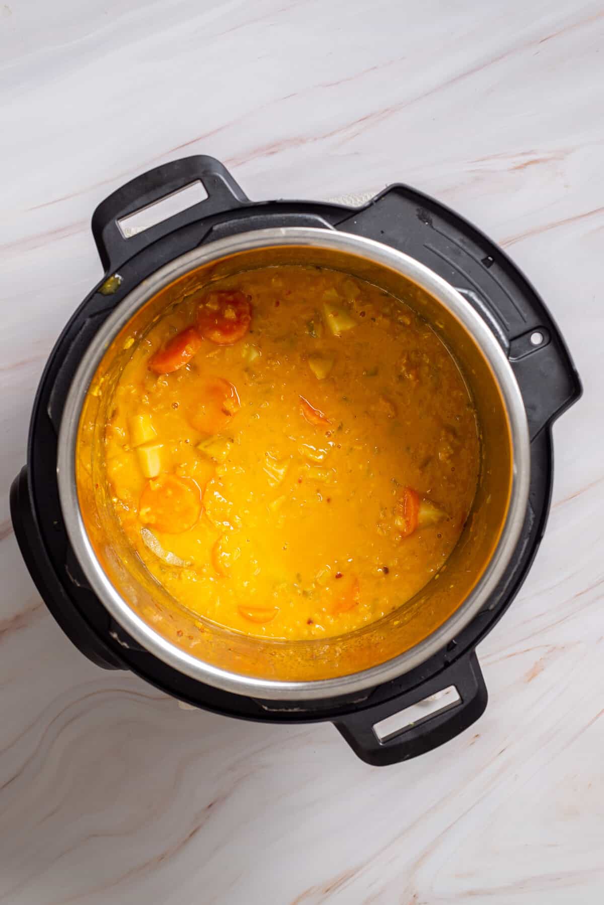 Overhead view of simmered mulligatawny soup in an instant pot, added with coconut milk.
