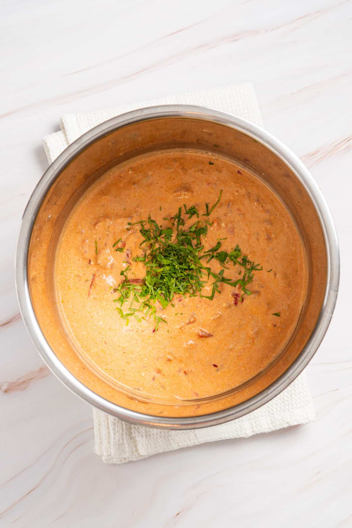 An overhead image of queso in an instant pot with cilantro on top.