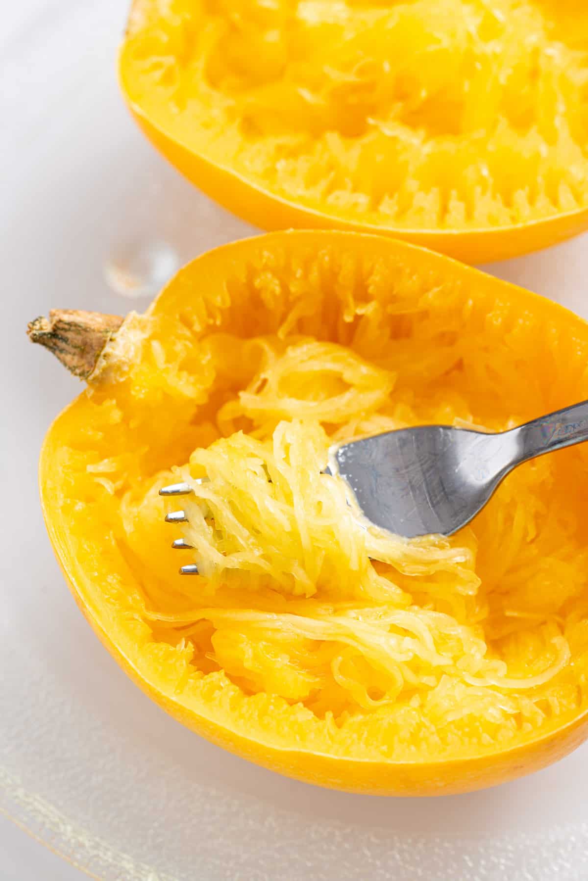 A close up image of spaghetti squash with strands shredded using a fork.