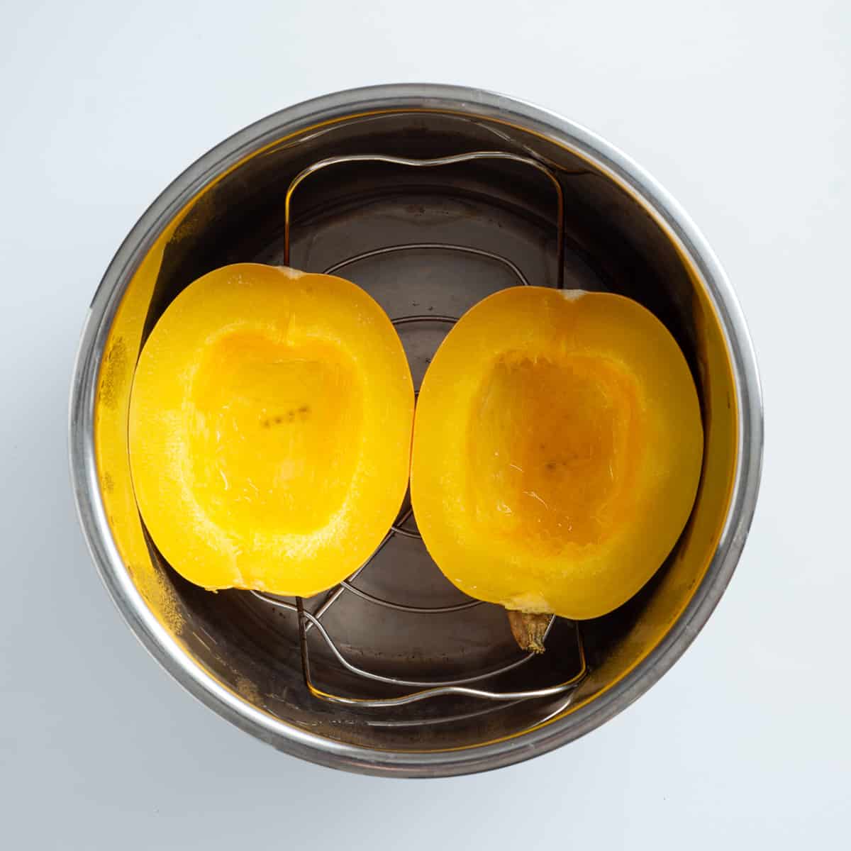 An overhead image of two spaghetti squash halves in an instant pot, before cooking.