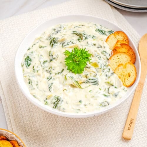 Overhead view of the spinach artichoke dip in a white bowl.