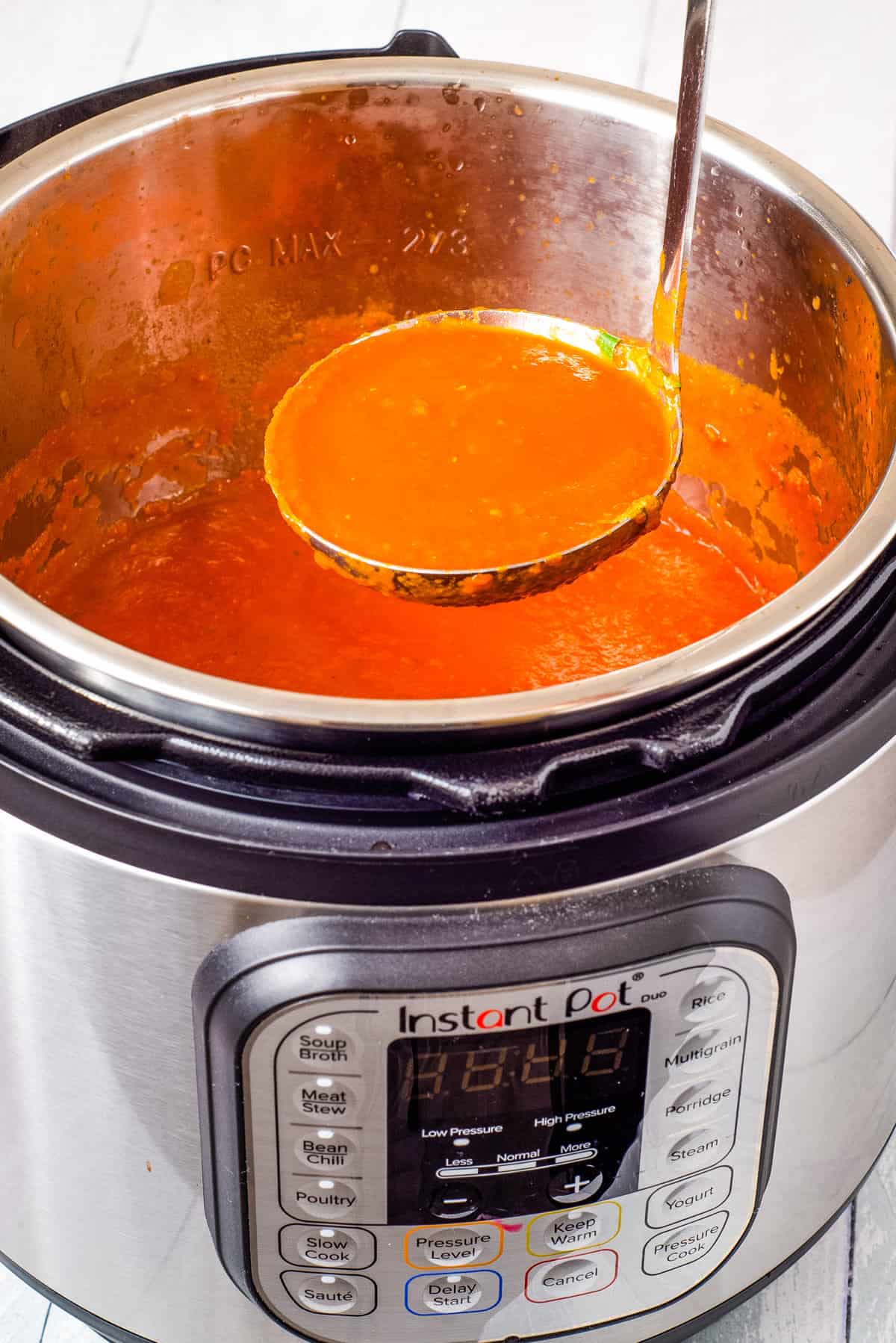 A close-up view of tomato soup being scooped out of the instant pot.