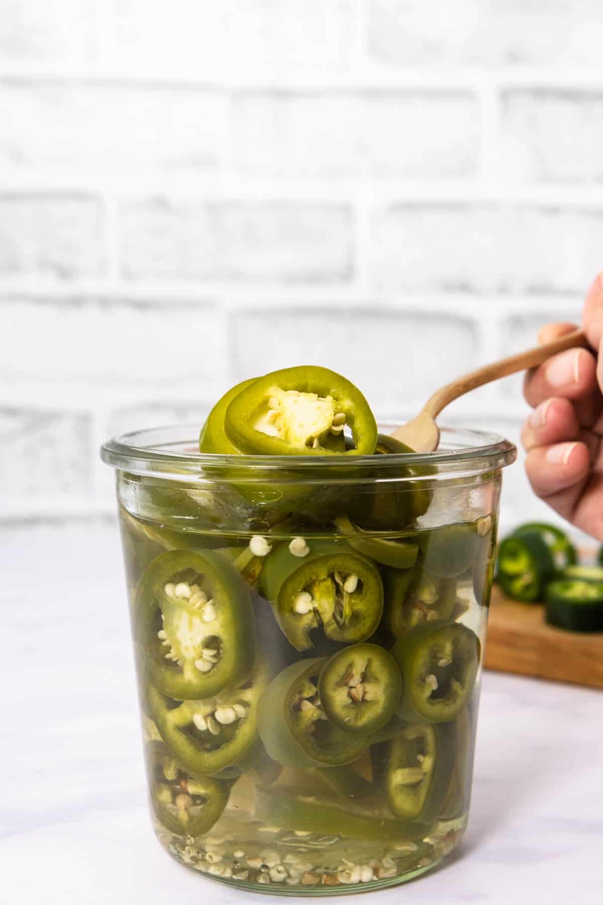 Jar of pickled jalapeños with fork lifting some of it 