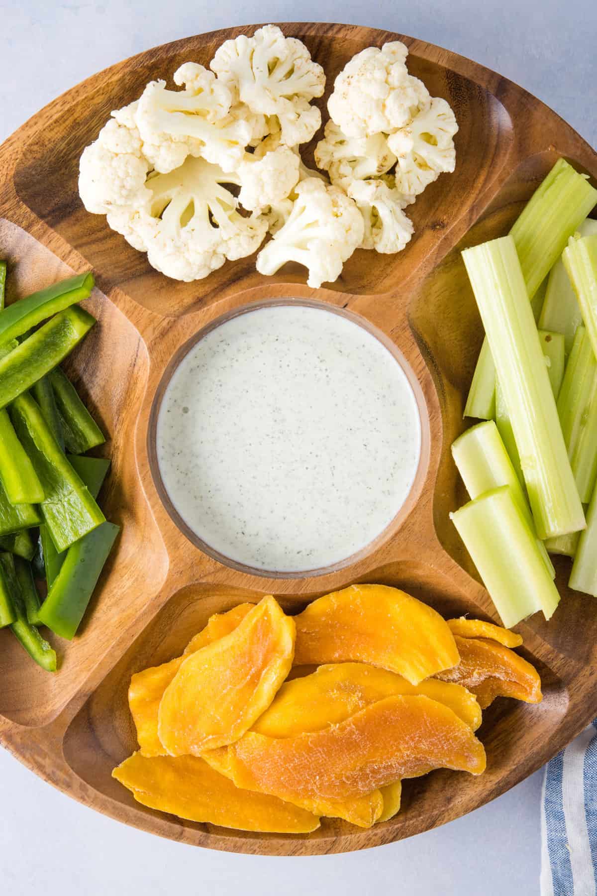 An overhead image of jalapeno ranch dressing surrounded by different fresh vegetables to use as a dipping sauce.
