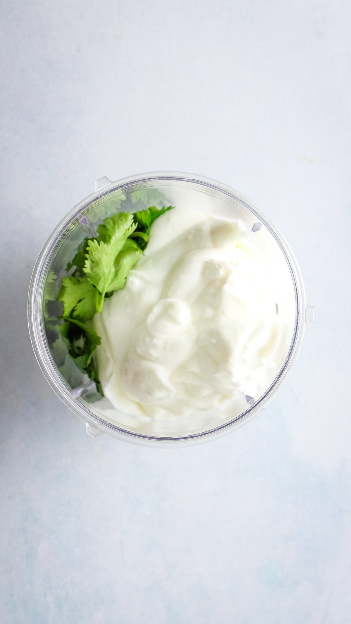 An overhead image of Greek yogurt and cilantro in a blender.