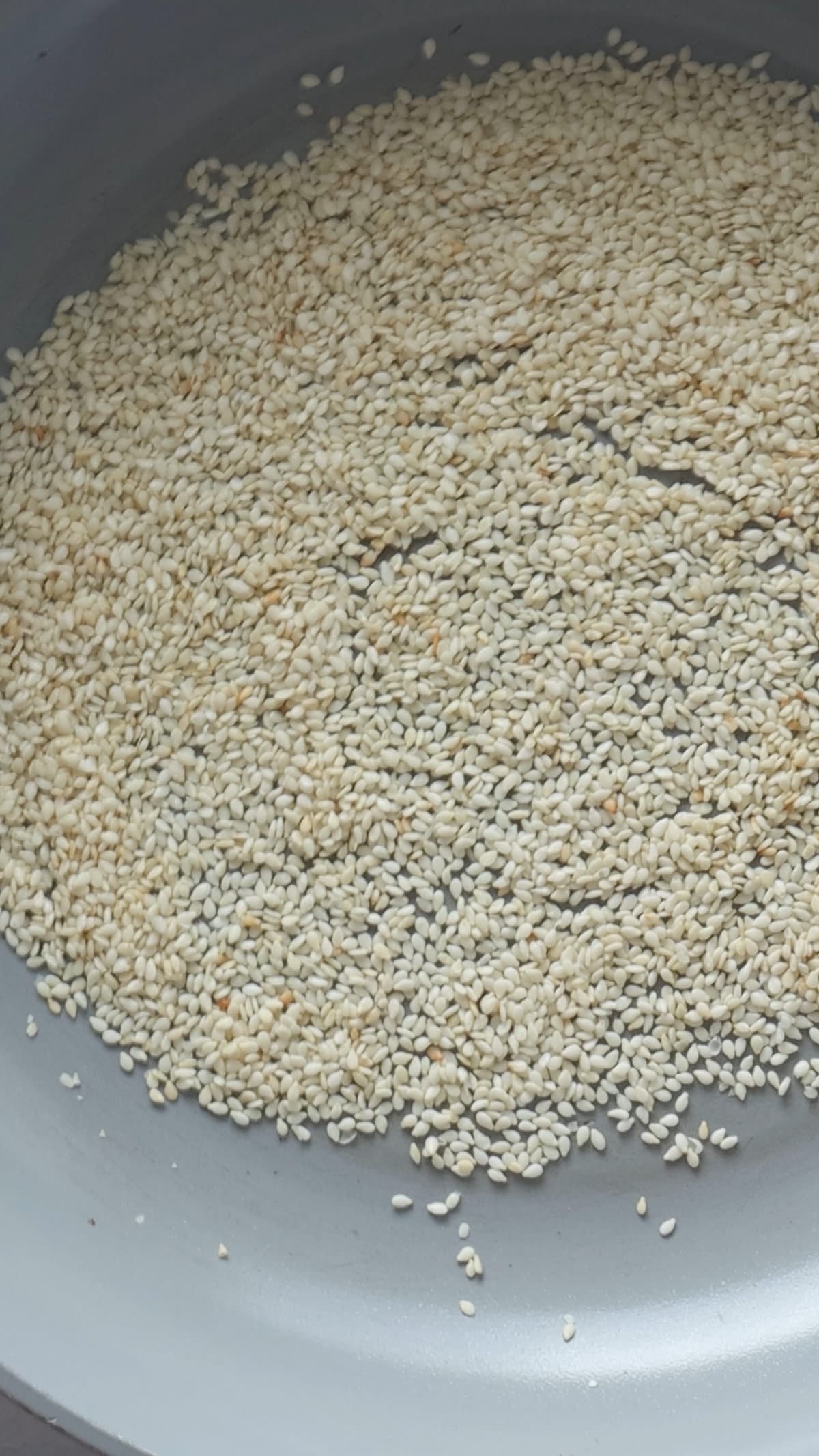 An overhead image of sesame seeds being toasted.
