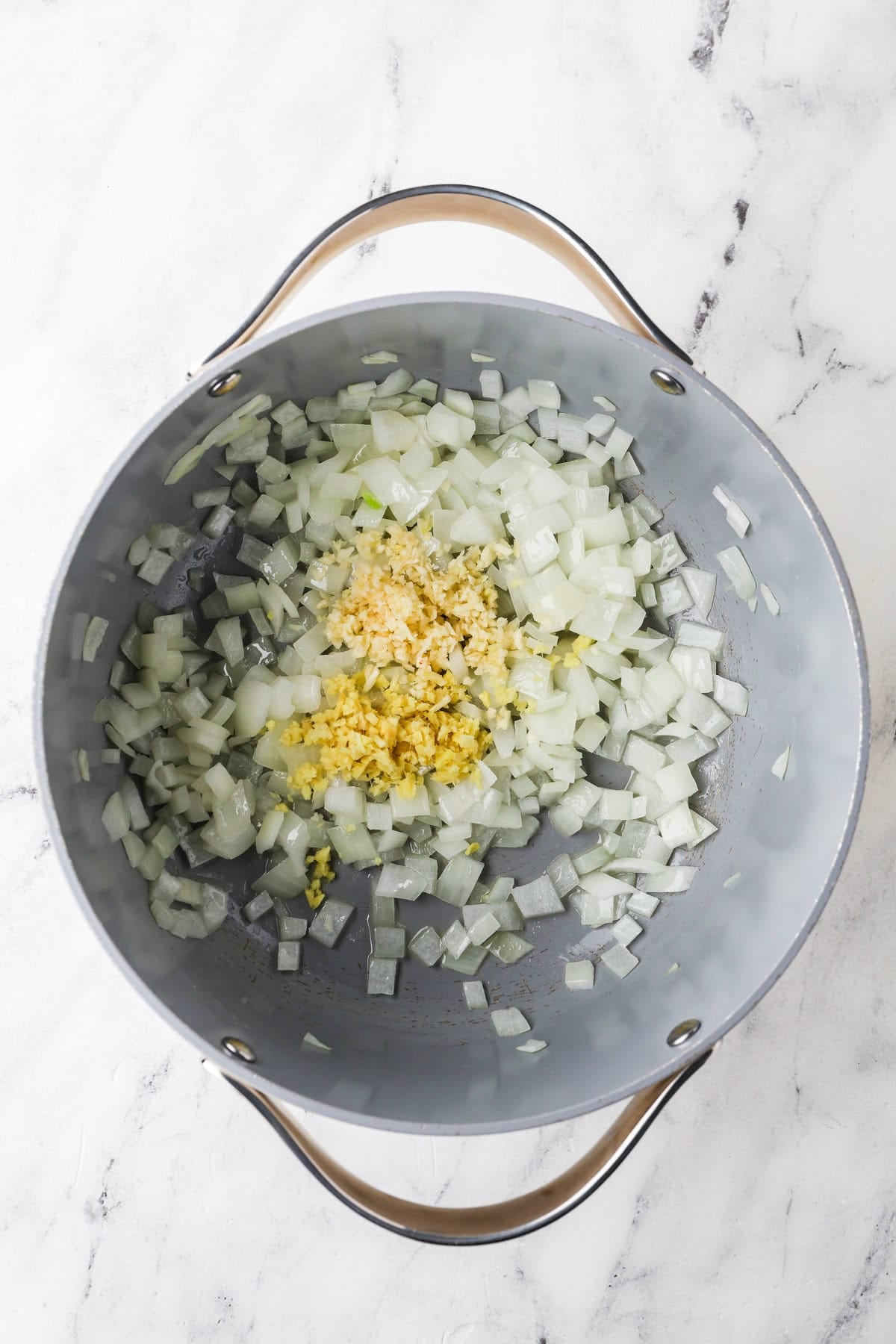 An overhead image of sauteing onions, garlic, and ginger.