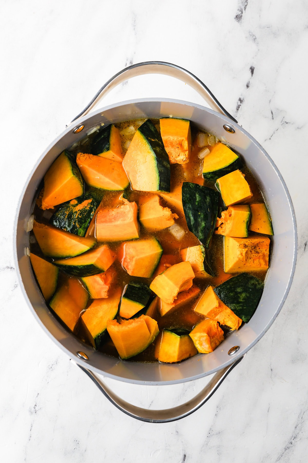 An overhead image of adding kabocha squash to the pot.