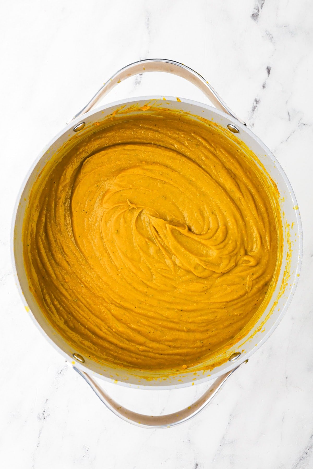An overhead image of blending the soup with an immersion blender.