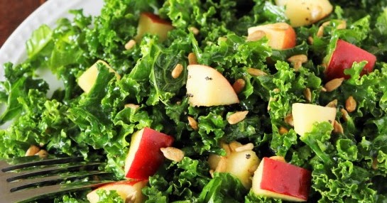 Overhead view of kale salad with apples and honey.