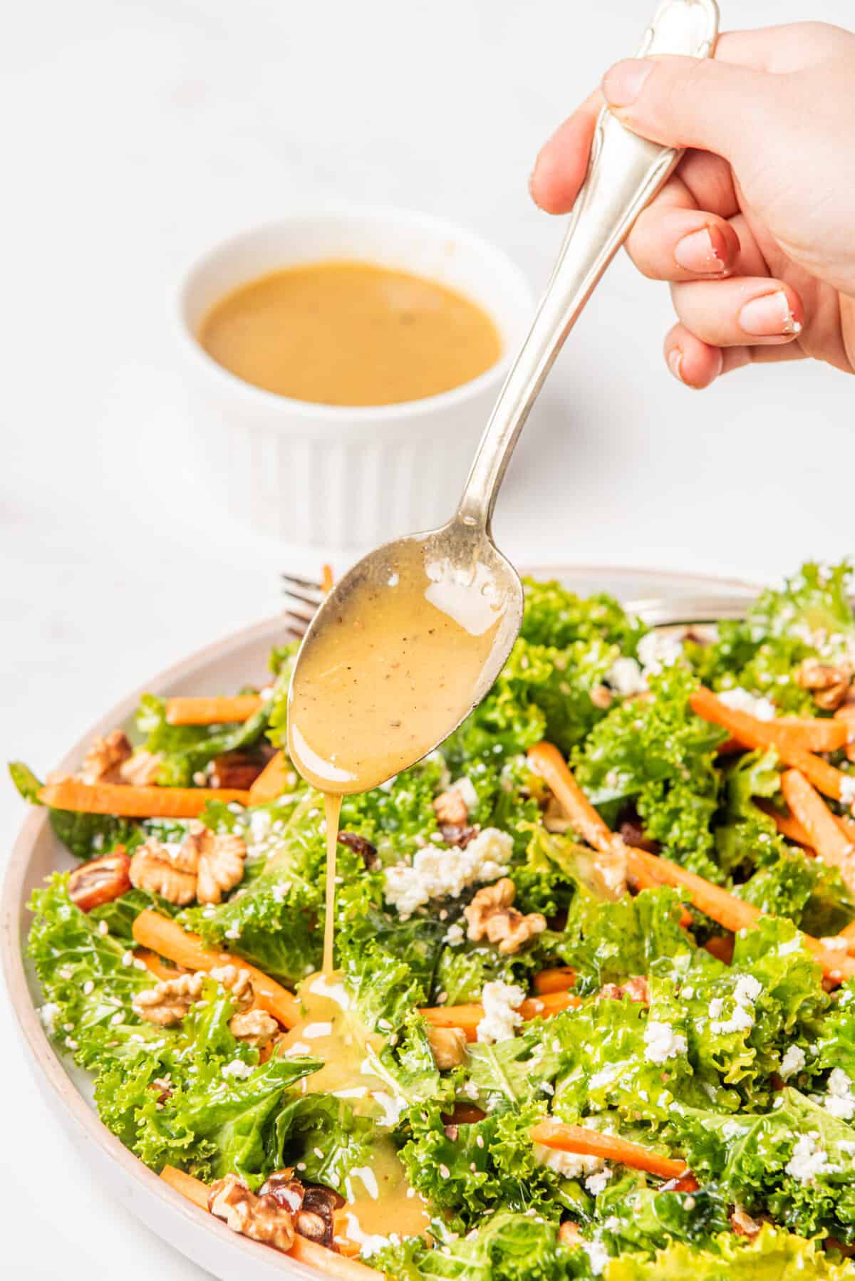 An image of fall kale salad with the dressing being drizzled over it.