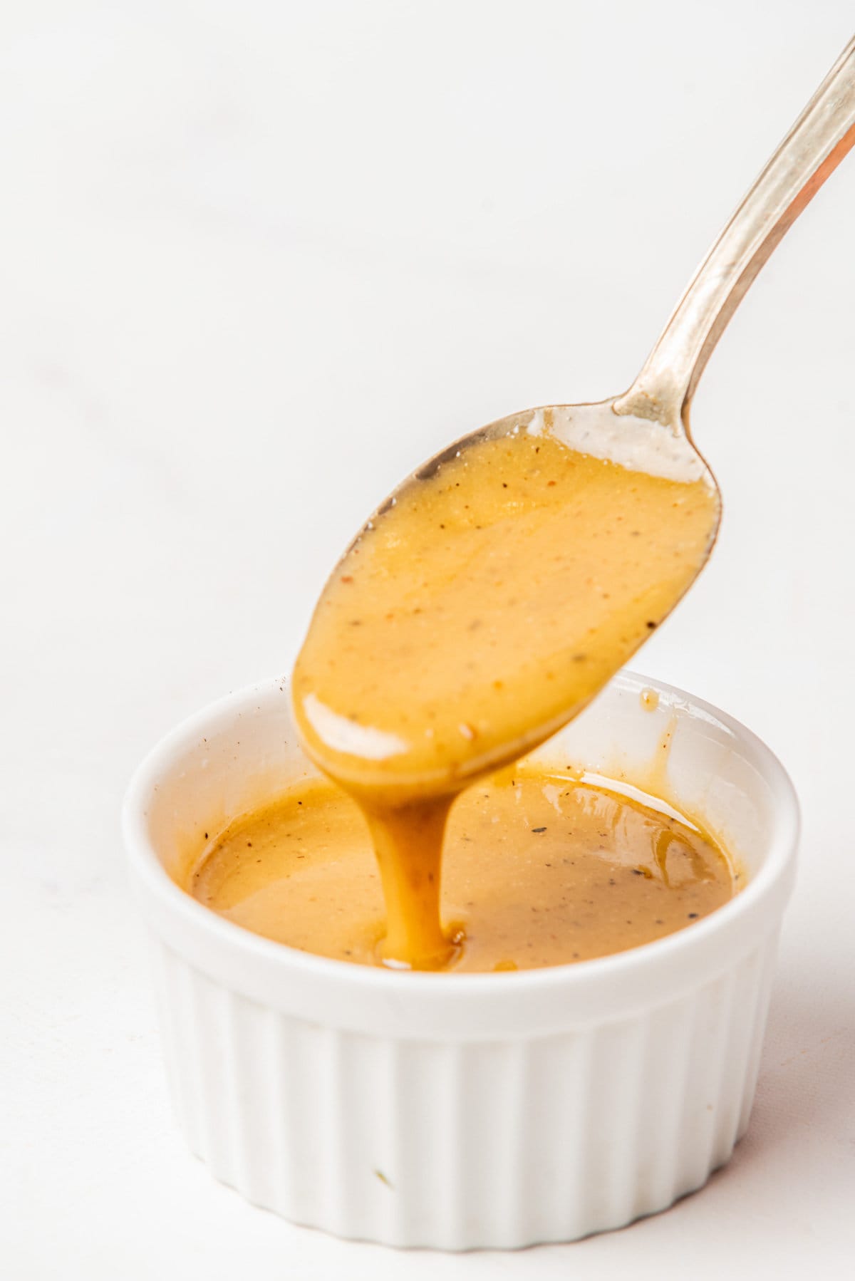 An image of salad dressing in a small bowl with aa spoon scooping a spoonful of dressing.
