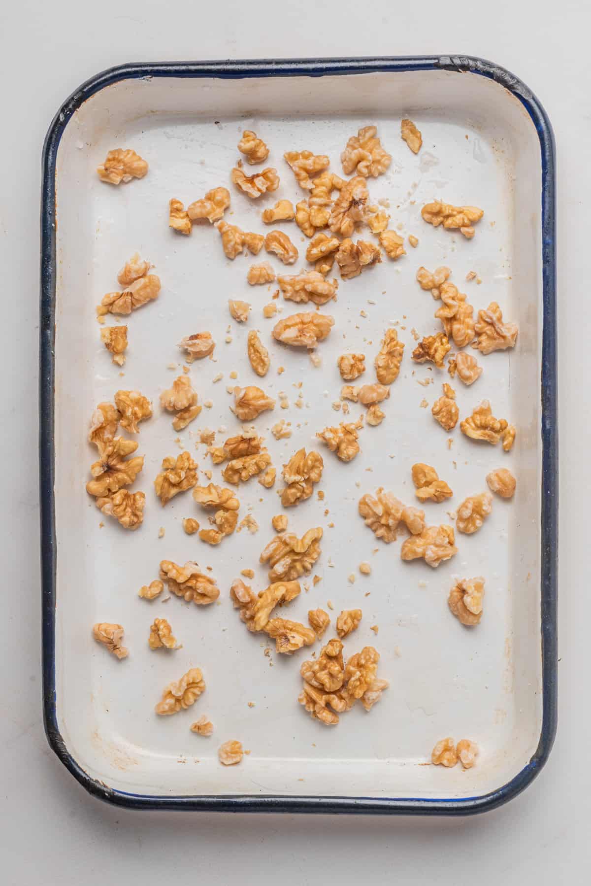 An overhead image walnuts spread out on a baking sheet.