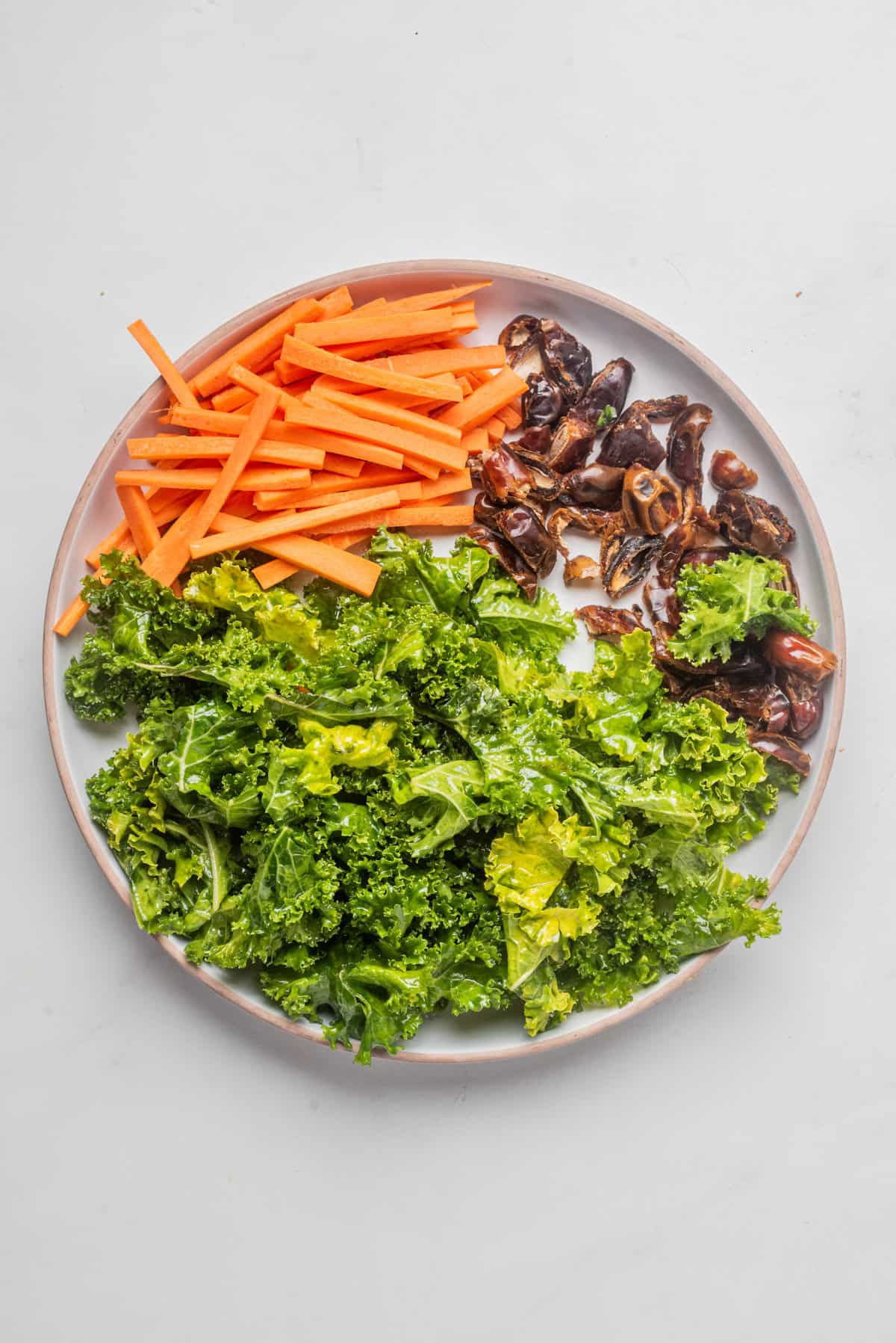 An image of carrots, kale, and walnuts side by side on a plate.